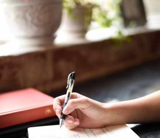 “스트레스, 자연스럽게 풀기… 새롭게 떠오르는 ‘슬로우 라이프’ 실천 팁” a person writing on a piece of paper with a pen